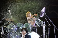 ドラムを叩きながら激しく水をまき散らすYOSHIKI。手前はToshI。