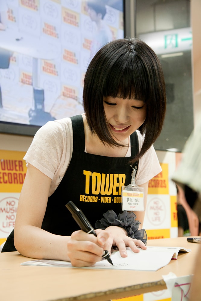 「FREECELL特別号 アキバ妄撮」にサインをする夢眠ねむ。