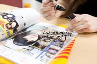 「FREECELL特別号 アキバ妄撮」にサインをする夢眠ねむ。