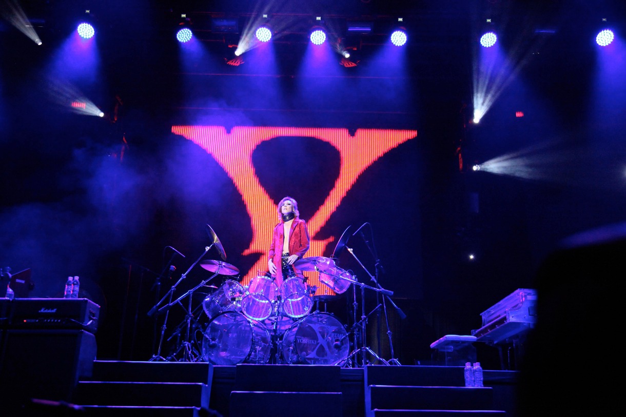 ドラムセットに仁王立ちになるYOSHIKI。