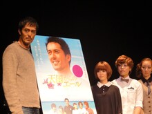 映画「天国からのエール」のポスターを囲んでの記念撮影に応じるステレオポニーと阿部寛。