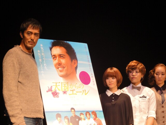 映画「天国からのエール」のポスターを囲んでの記念撮影に応じるステレオポニーと阿部寛。