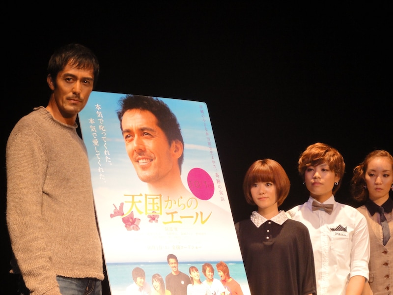 映画「天国からのエール」のポスターを囲んでの記念撮影に応じるステレオポニーと阿部寛。