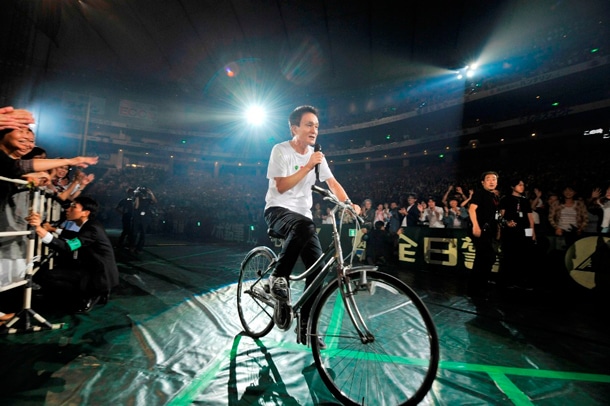 客席エリアを自転車で快走しながら「キラキラ」を歌う小田和正。（撮影：菊地英二）