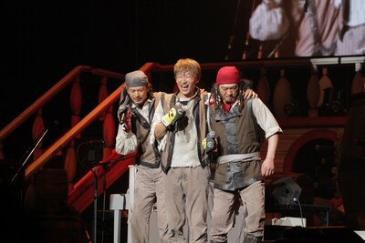 「メダカの格好」を歌うEBI、川西、テッシー。この曲では、3人の足がマジックテープで結ばれており、3人4脚のかたちで左右に移動するパフォーマンスが観られた。