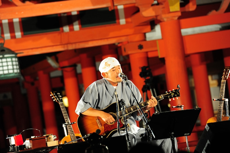 嚴島神社の祓殿をバックに熱唱する民生。