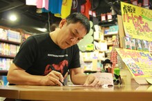 サインを記入しているピエール瀧。