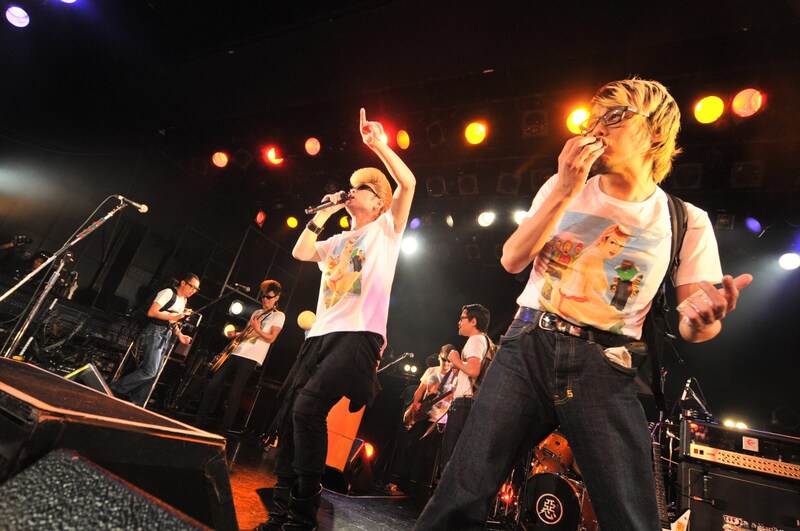 歌そっちのけでおにぎりにかぶりつくTAKUMAと、「はじめてのチュウ」を熱唱する綾小路翔（撮影：小川舞）。