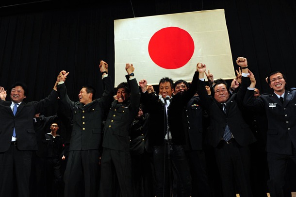 自衛隊員と手をつないで記念撮影する長渕剛と一川防衛大臣。