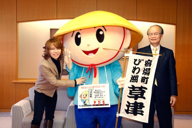 西川貴教（写真左）、草津市の観光マスコットキャラクターたび丸（中央）、橋川渉市長（右）。