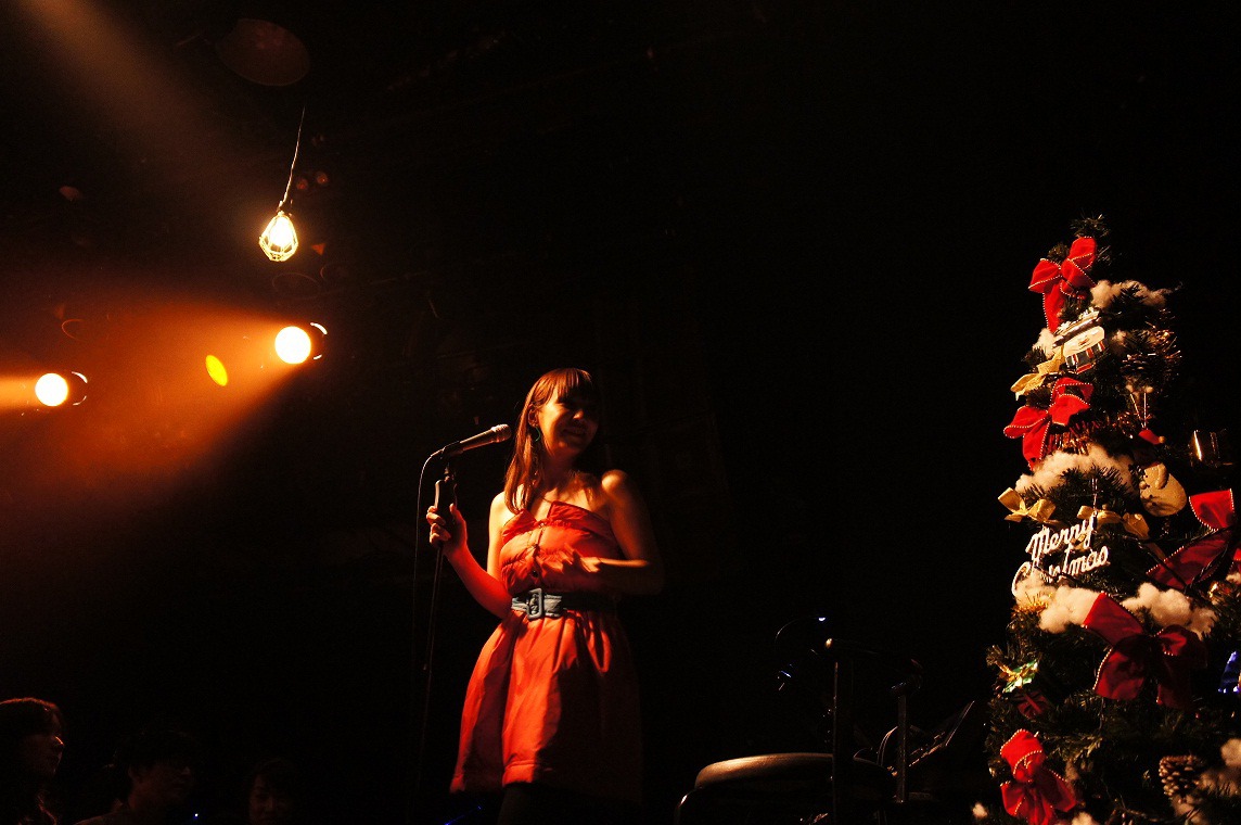 クリスマスツリーの横で歌う土岐麻子。