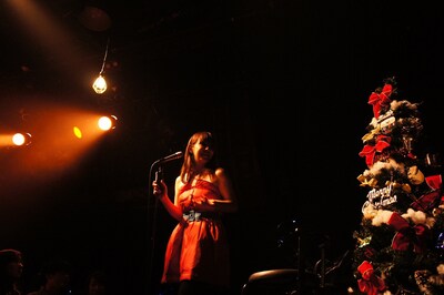 クリスマスツリーの横で歌う土岐麻子。
