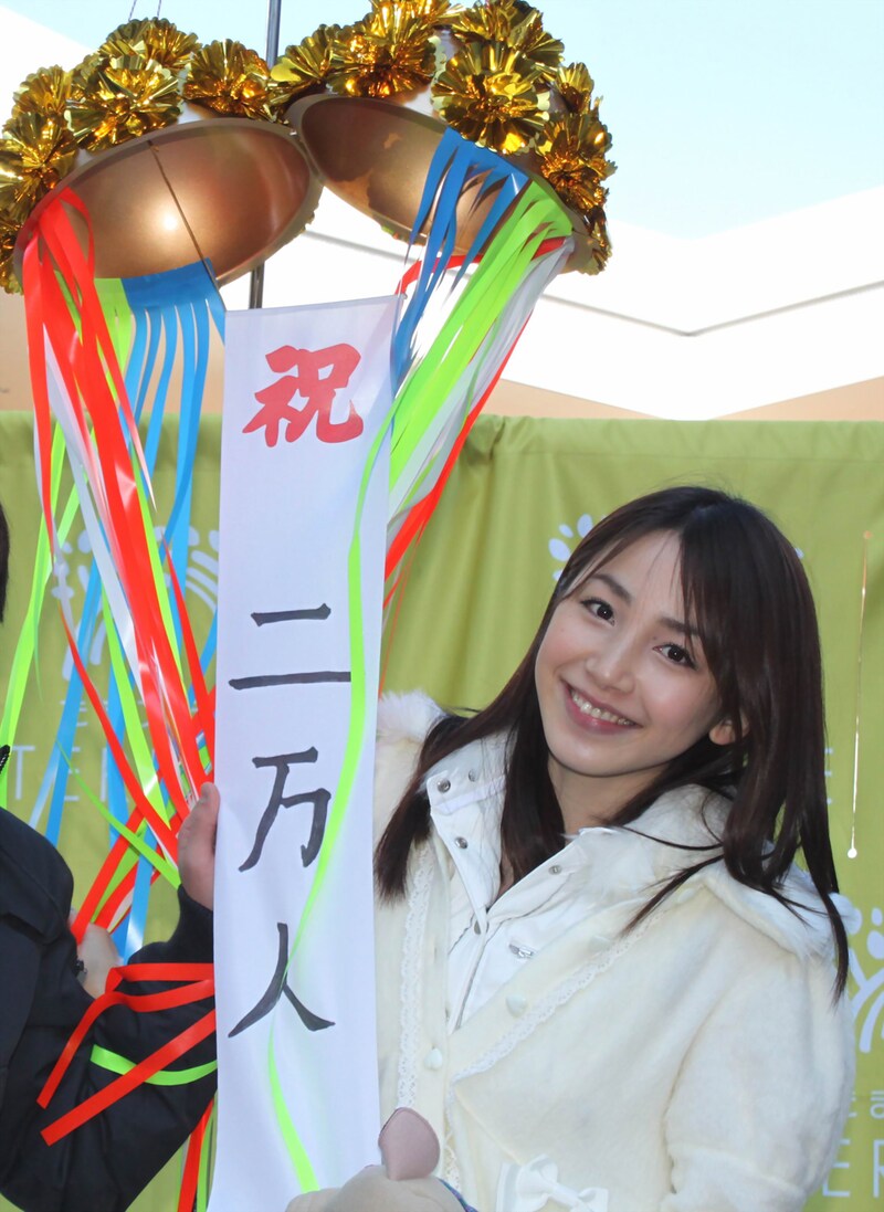 笑顔でくす玉を割って、握手通算2万人目のファンを祝福する吉川友。