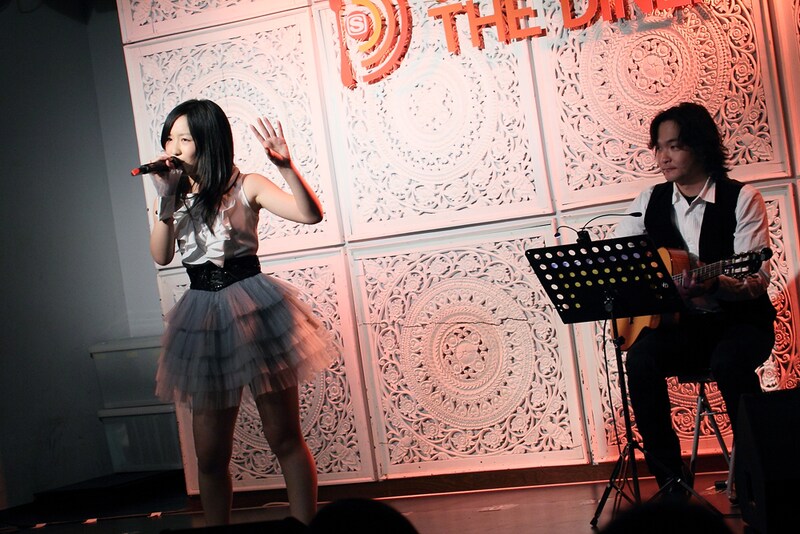 ボサノバ調にアレンジされた「Bomb a Head!」を歌う小西彩乃（写真左）。