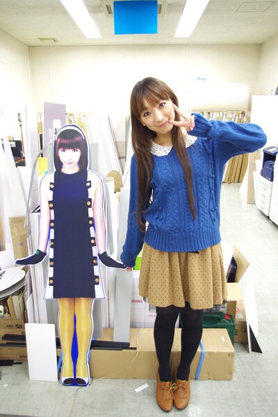 完成した自分の全身POPとツーショット撮影するほっちゃん。