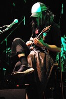 骨折のため座ったままギターを弾くNARASAKI。