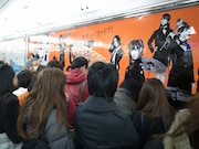 ギターピックに気付き、大型ポスターに集まる通行人。