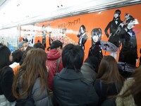 ギターピックに気付き、大型ポスターに集まる通行人。