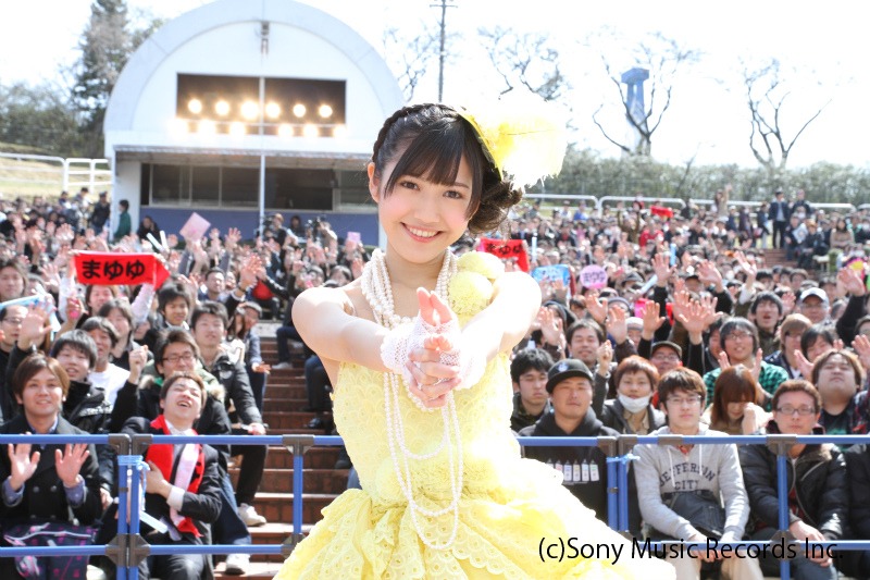 会場のファンを背に、ハートを撃ち抜くポーズを取るまゆゆ。