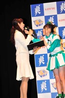 写真は本日行われたロッテアイス「爽」新CM記者発表会より。「口の中でさらーっと溶けちゃう」と「爽」を食べた感想を伝えた有安杏果（写真右）は女性MCにおすそわけ。