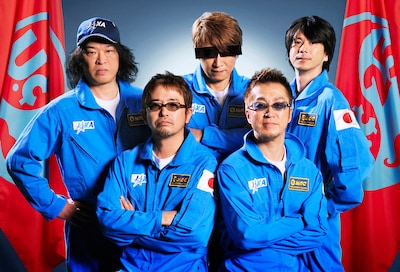 ユニコーンの新しいアーティスト写真もお披露目。JAXAブルースーツ姿の5人の後ろには「Uc25」フラッグが。ちなみにユニコーンは今年10月21日でデビュー25周年を迎える。