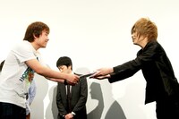 「映画『ロボット』キャッチコピー選手権」のグランプリ受賞者に賞金を手渡す鬼龍院。