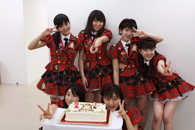 ロゴ入りケーキを前に記念撮影するスマイレージ。