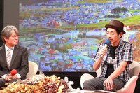 宮藤官九郎（写真右）と番組プロデューサー（左）。背後のスクリーンに投影されているのは、ロケ地となる岩手県久慈市の様子。