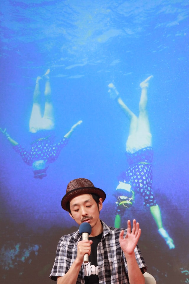 久慈の海に潜る海女をバックに、舞台背景を説明する宮藤。