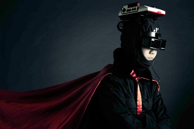 日本が誇るゲーム器、ファミリーコンピュータを頭に乗せて演奏するサカモト教授。