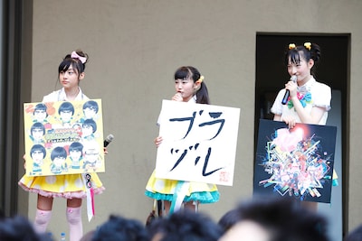 写真は昨日7月22日のステージより。ジャケット拡大パネルを持った鈴木裕乃、柏木ひなた、松野莉奈（左から）。