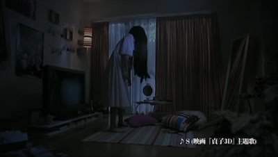 部屋に置かれた雑誌に見入る貞子。