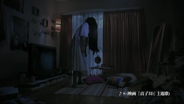 部屋に置かれた雑誌に見入る貞子。