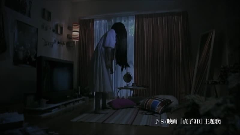 部屋に置かれた雑誌に見入る貞子。