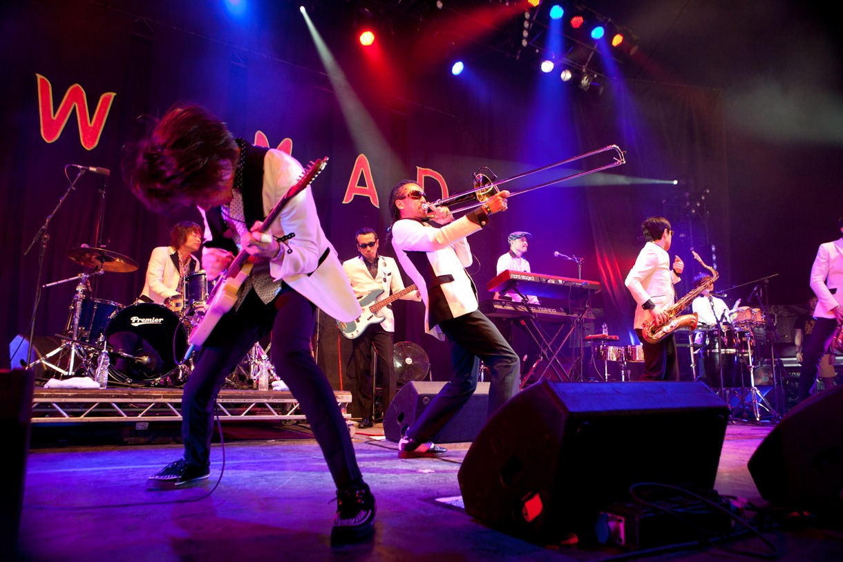 写真は「WOMAD UK 2012」での東京スカパラダイスオーケストラのライブの模様（撮影：仁礼博）。