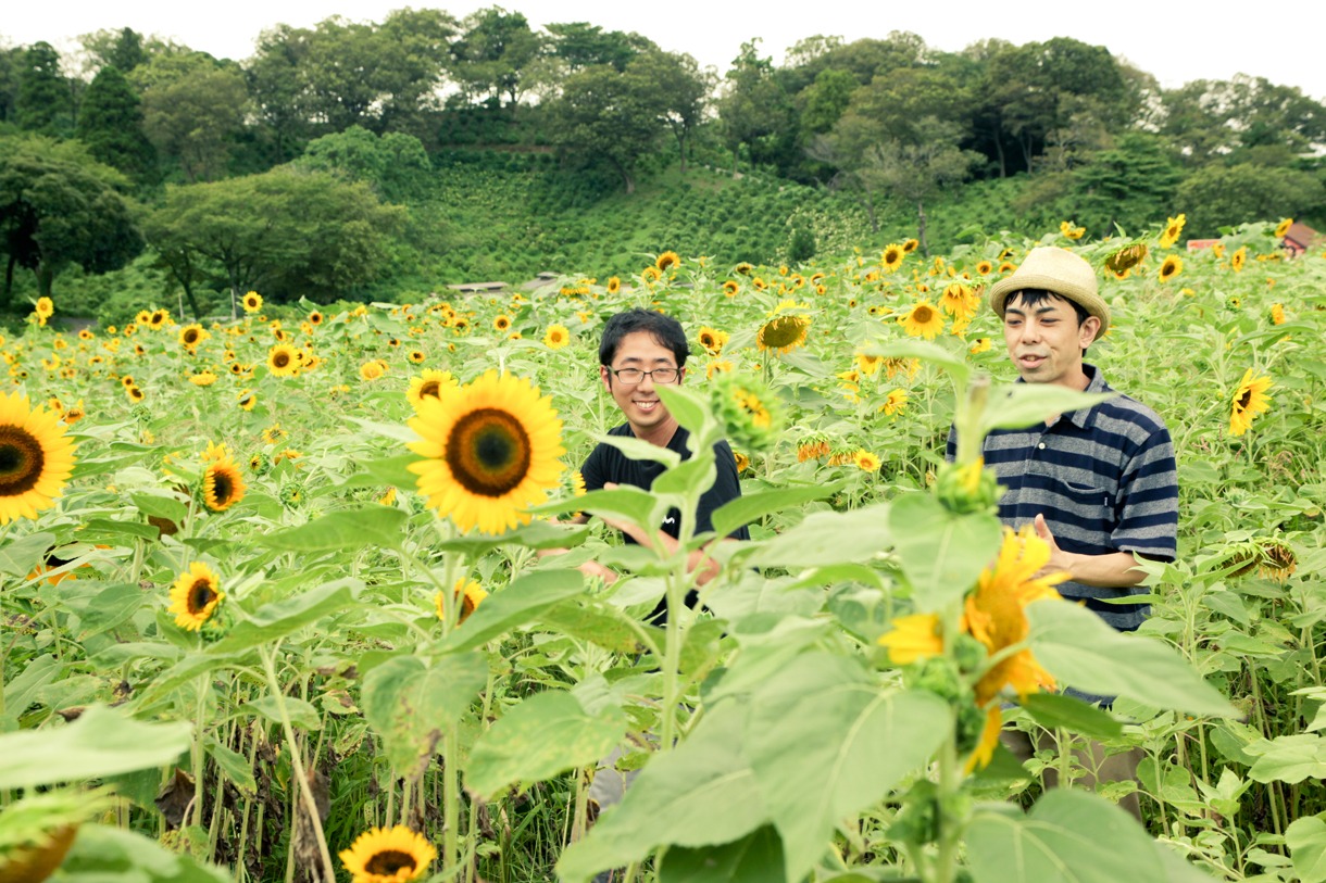ひまわり畑でたわむれるオノマトペ大臣（写真左）とナオヒロック（右）。