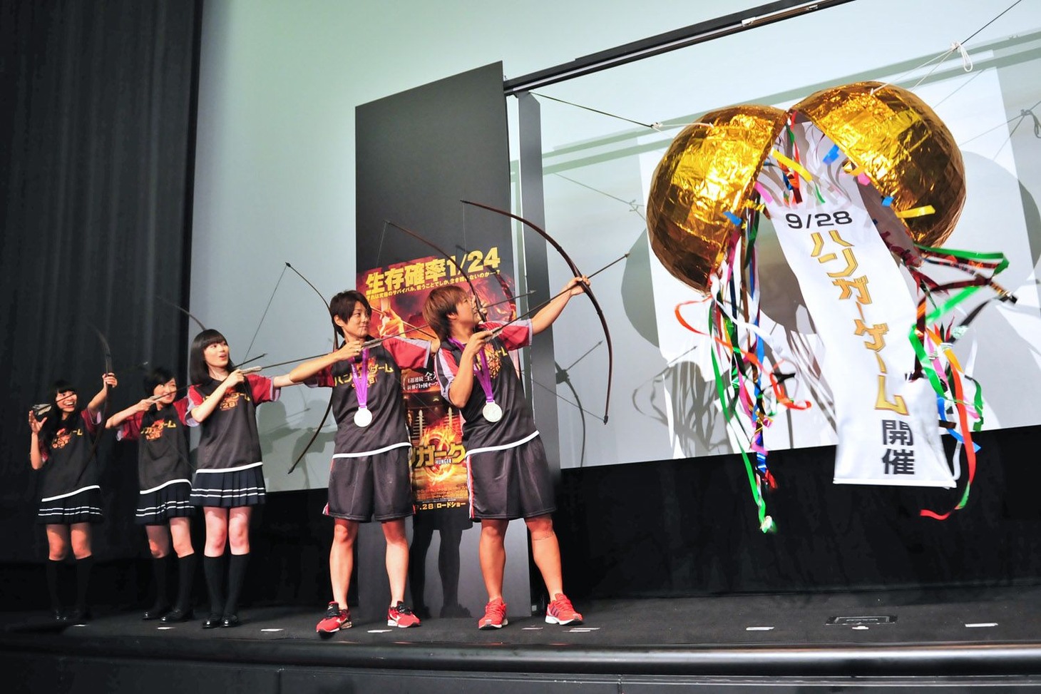 弓矢を使ってくす玉を割るゲストの5人。 (C) 2012 LIONS GATE FILMS INC. ALL RIGHTS RESERVED.