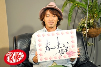 受験生へのメッセージ色紙を掲げるナオト・インティライミ。