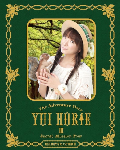 堀江由衣「堀江由衣をめぐる冒険III ～Secret Mission Tour～」Blu-ray盤ジャケット。ライブの世界観を表現し「森の中」をテーマ制作されており、動物たちと戯れるほっちゃんが印象的なデザインに仕上がっている。