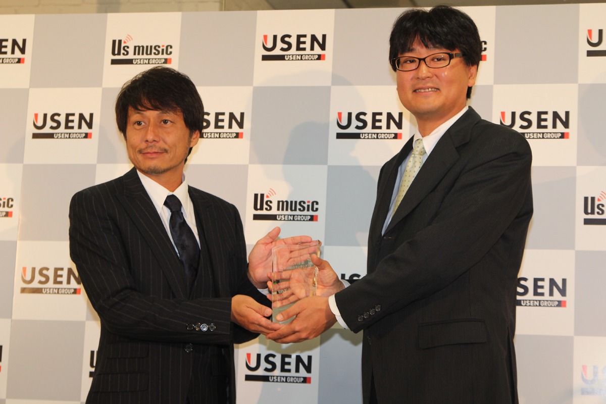 USENグループ会長・宇野康秀から記念の盾を受け取る、ソニー・ミュージックジャパンインターナショナル代表取締役・石橋正。
