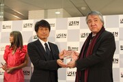 USENグループ会長・宇野康秀から記念の盾を受け取る、EMI Music Japan代表取締役会長・行方均。