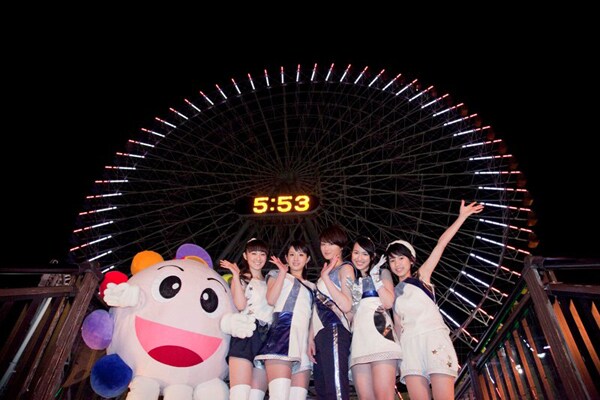 「COSMOの瞳」をイメージしたイルミネーションが点灯されたコスモクロック21の前で記念撮影するbump.yとコスモくん。