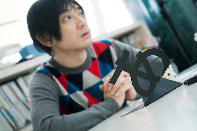 「デザインあ」の特殊仕様ジャケットを前にインタビューに応じる小山田圭吾。