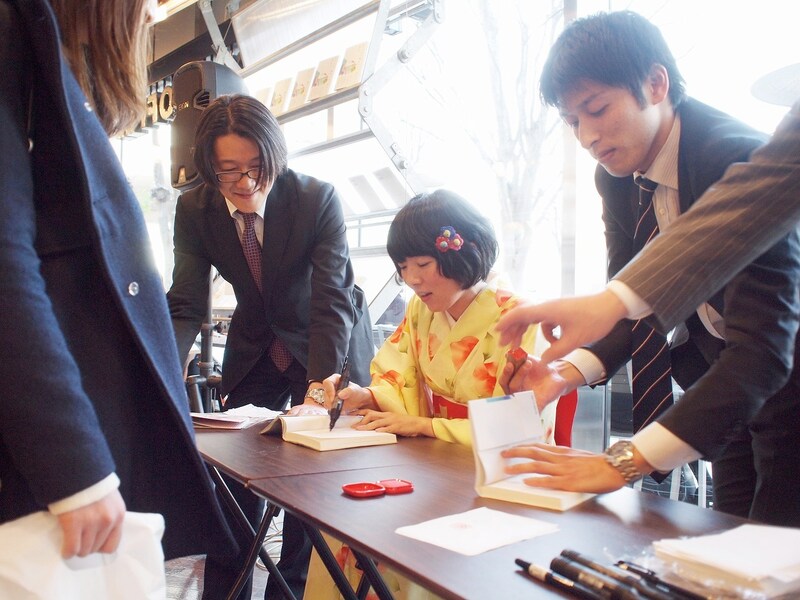 自著「思いつつ、嘆きつつ、走りつつ、」にサインをする高橋久美子。