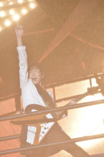 びしょ濡れになりながらギターを弾くShinji（G）。（撮影：江隈麗志）