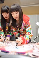 急遽集まったモノノフへのプレゼント用にサインを書く高城れに（写真左）と百田夏菜子。