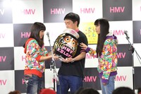 以前メンバーが目を入れただるまにサインを書く百田夏菜子。なお、だるまがかぶっているのはももクロオフィシャルファンクラブ「ANGEL EYES」入会特典のベレー帽。