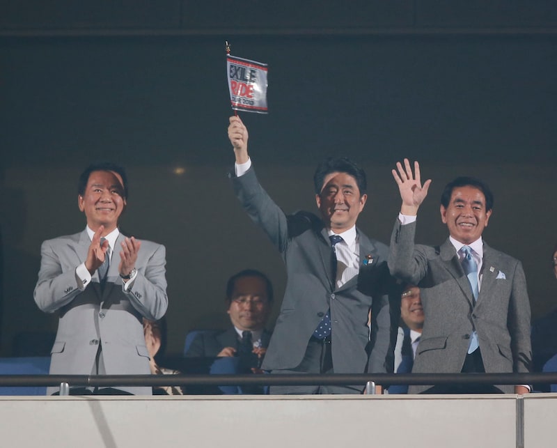 「EXILE LIVE TOUR 2013 “EXILE PRIDE”」のフラッグを掲げる安倍晋三首相(写真中央)。