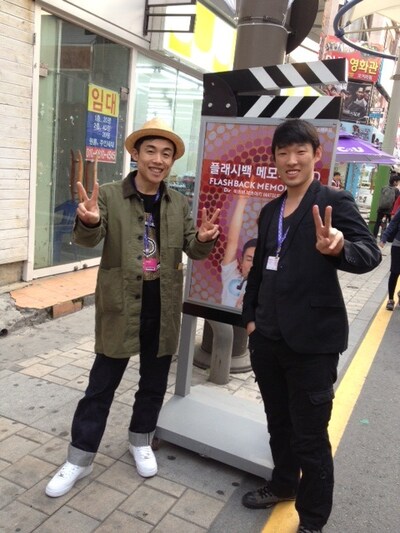 シネマストリートでポスター前に立つGOMA（写真左）と松江哲明（右）。