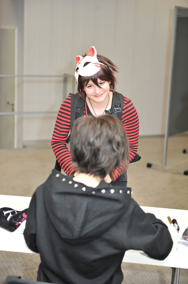 “ちびナノ”のコスプレをした海外ファンにサインをするナノ（手前）。